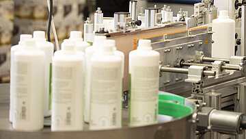 Maschine mit Flasche und Frau die diese befüllt